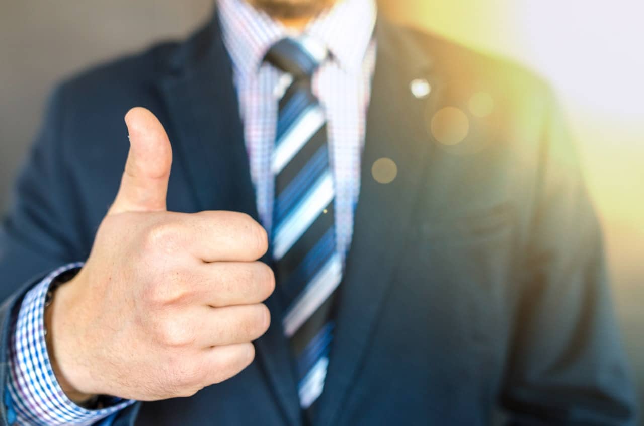 Man wearing black suit doing thumbs up